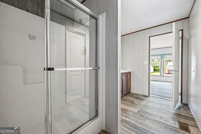 full bathroom featuring wood finished floors, a stall shower, ornamental molding, and vanity
