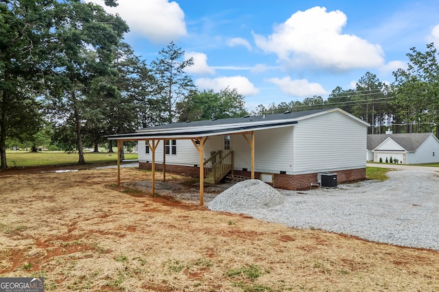 view of home's exterior featuring central air condition unit, driveway, crawl space, and a carport