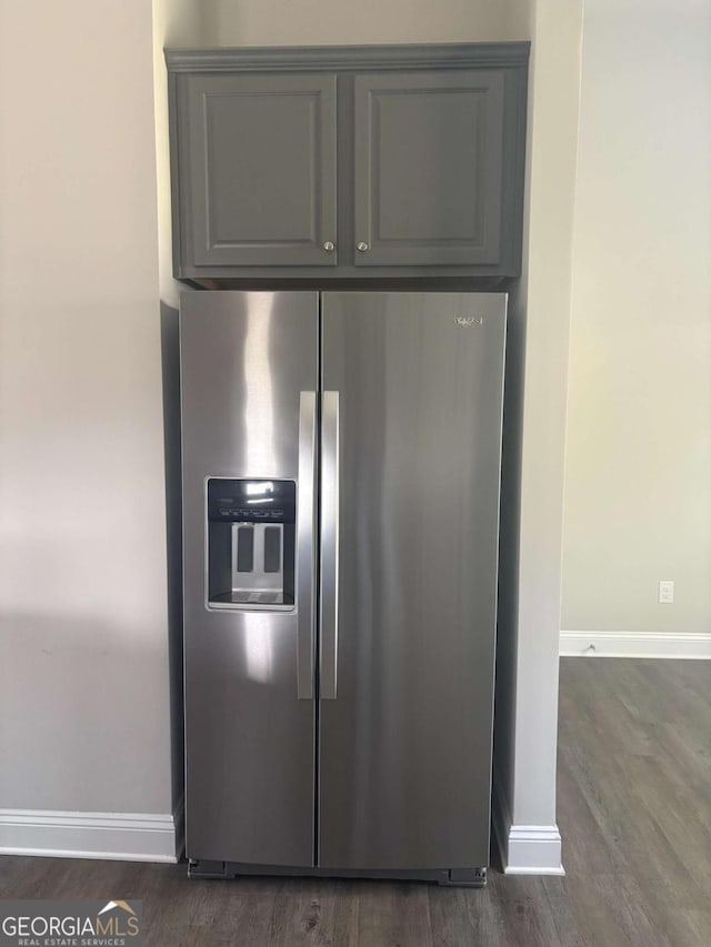 kitchen view of stainless steel fridge, gray cabinetry, dark wood-style floors, and baseboards