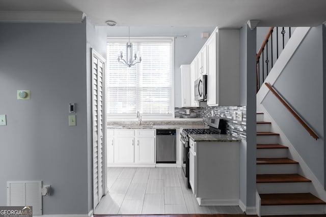 kitchen with appliances with stainless steel finishes, a chandelier, white cabinetry, and plenty of natural light