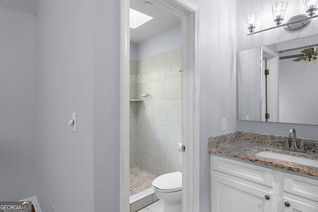 bathroom featuring toilet, a skylight, a shower stall, and vanity
