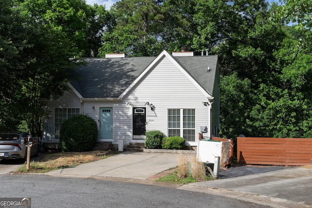 view of front of home featuring entry steps, fence, a chimney, and roof with shingles