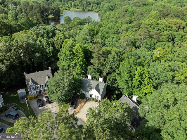 aerial view of property and surrounding area with a heavily wooded area and a nearby body of water