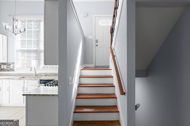 stairs featuring a chandelier and wood finished floors