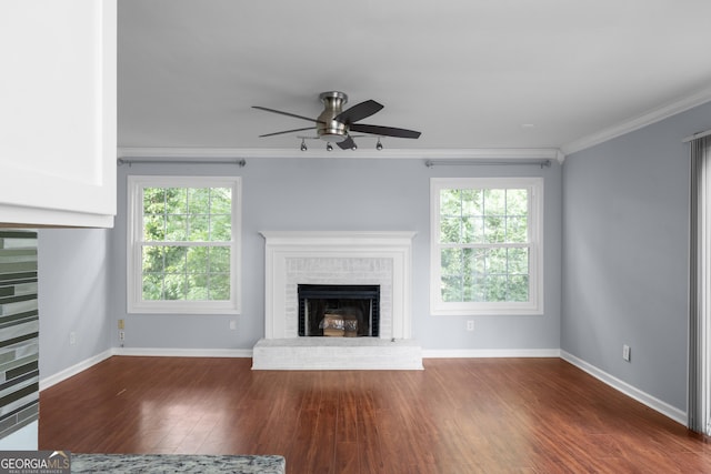 unfurnished living room with a fireplace, a ceiling fan, crown molding, baseboards, and wood finished floors