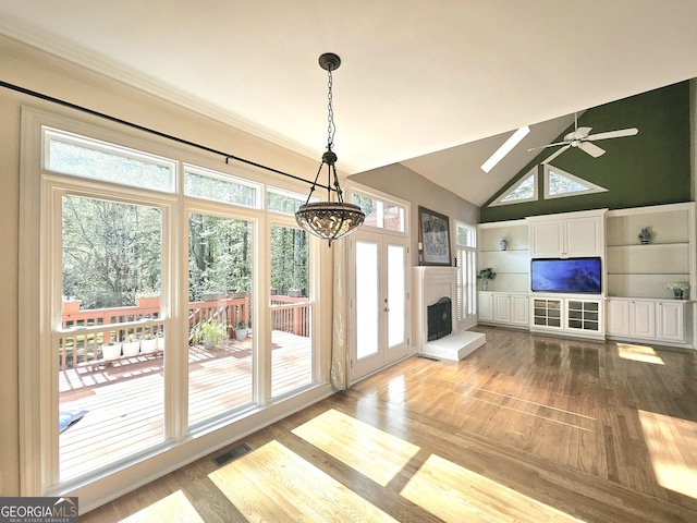 unfurnished living room with light wood-style floors, a chandelier, a fireplace with raised hearth, ceiling fan, and high vaulted ceiling