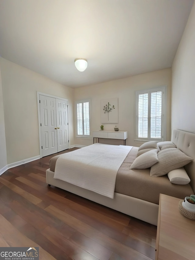 bedroom with wood finished floors, a closet, and baseboards