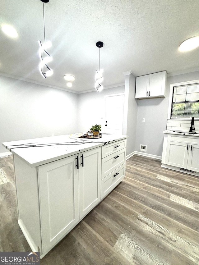 4516 Bon Ayer Cir, Macon, GA 31204 - kitchen with white cabinets, a textured ceiling, light countertops, wood finished floors, and pendant lighting