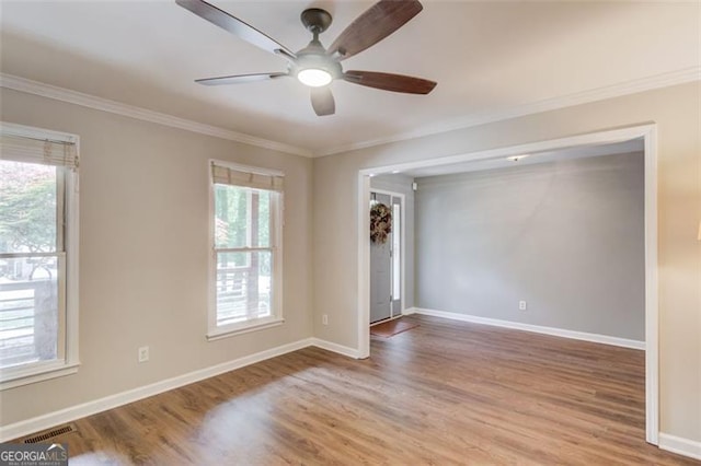 empty room featuring ornamental molding, plenty of natural light, light wood-style floors, and a ceiling fan