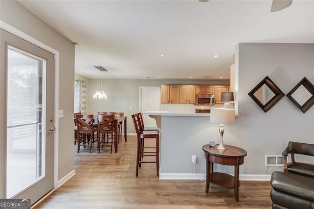 living area featuring light wood-style floors, baseboards, recessed lighting, and a chandelier