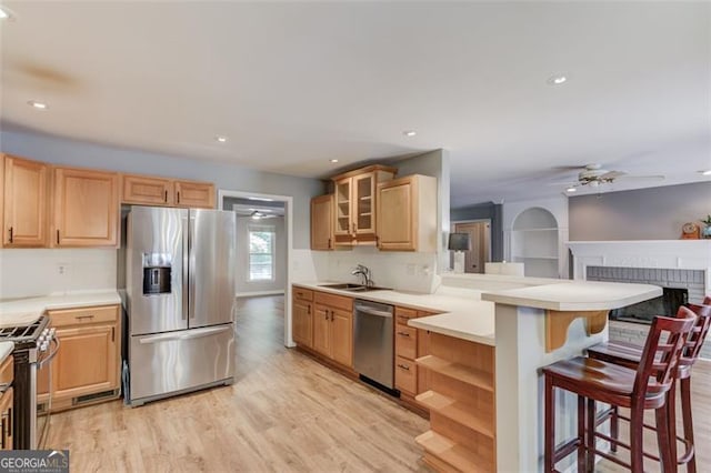 kitchen featuring appliances with stainless steel finishes, light brown cabinetry, a breakfast bar area, a peninsula, and recessed lighting