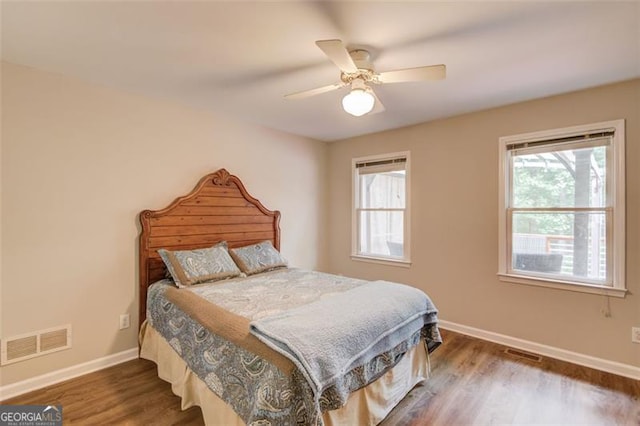 bedroom with multiple windows, baseboards, wood finished floors, and ceiling fan