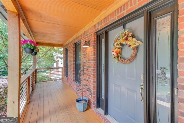 doorway to property with a porch and brick siding