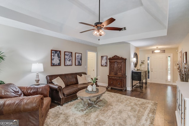 living area featuring a raised ceiling, dark wood-type flooring, ceiling fan, and baseboards