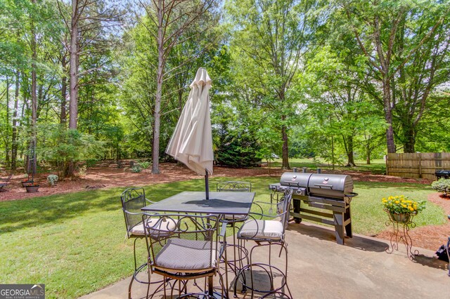 view of patio / terrace with outdoor dining space, view of scattered trees, and a grill