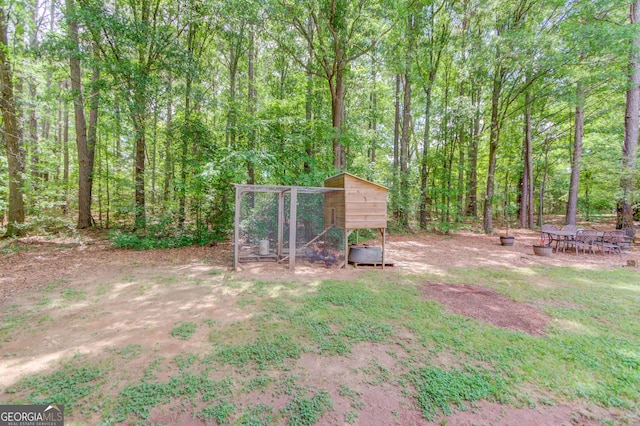 view of yard with exterior structure, an outdoor structure, and a forest view