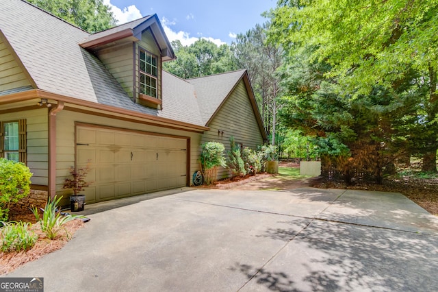 view of property exterior featuring roof with shingles and concrete driveway
