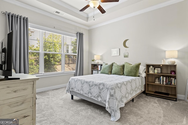 bedroom with light colored carpet, ornamental molding, a tray ceiling, baseboards, and a ceiling fan