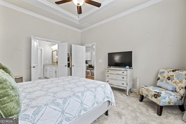 bedroom with light colored carpet, a raised ceiling, ornamental molding, a ceiling fan, and ensuite bath