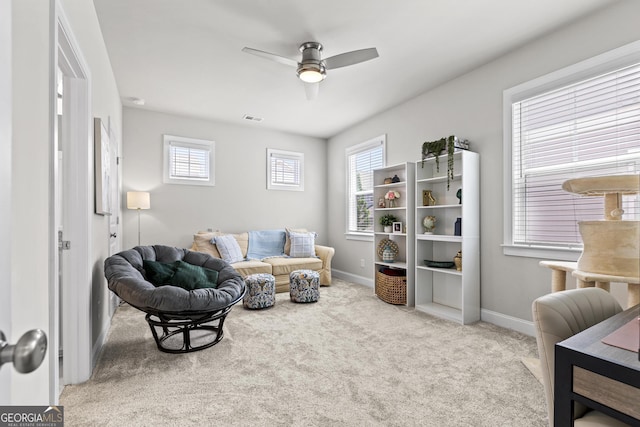carpeted living area with a ceiling fan and baseboards