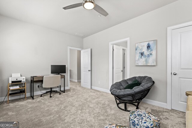 carpeted office space featuring a ceiling fan and baseboards
