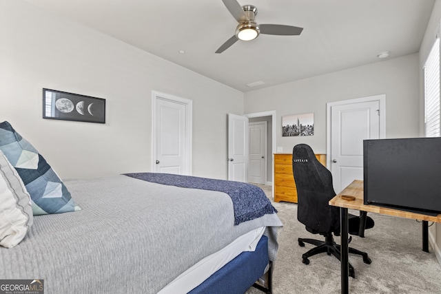 carpeted bedroom with an office area and ceiling fan