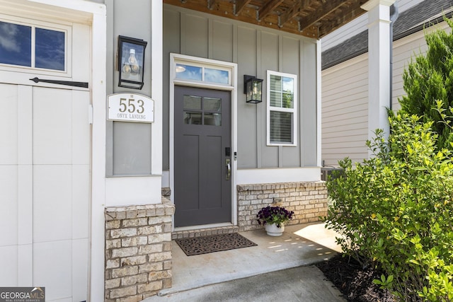 view of exterior entry with board and batten siding and a porch