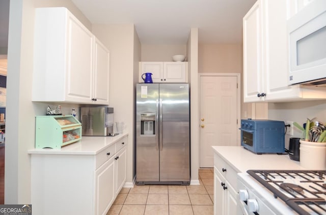 kitchen with white appliances, white cabinets, light countertops, and light tile patterned flooring