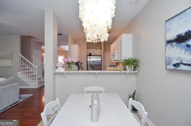 dining area featuring stairway, a chandelier, wood finished floors, and baseboards