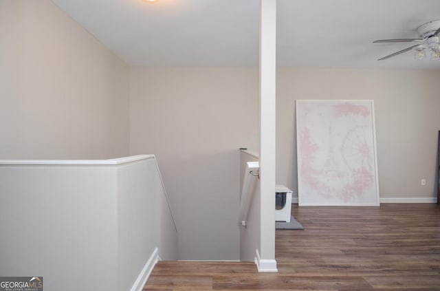stairway with a ceiling fan, wood finished floors, and baseboards