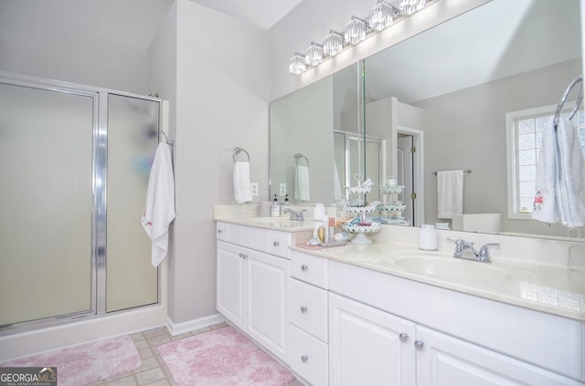 bathroom featuring a stall shower, double vanity, and baseboards