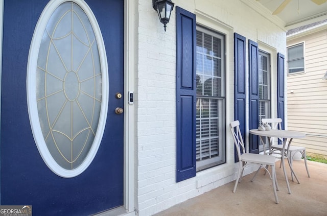 view of exterior entry featuring a porch and brick siding