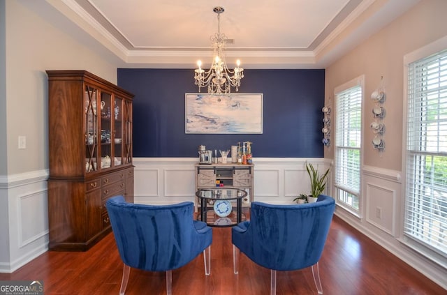sitting room with a chandelier, a tray ceiling, a decorative wall, wood finished floors, and wainscoting