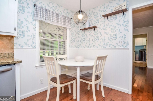 dining space with wood finished floors, wainscoting, and wallpapered walls