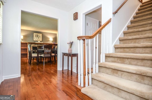 stairway with hardwood / wood-style flooring and baseboards