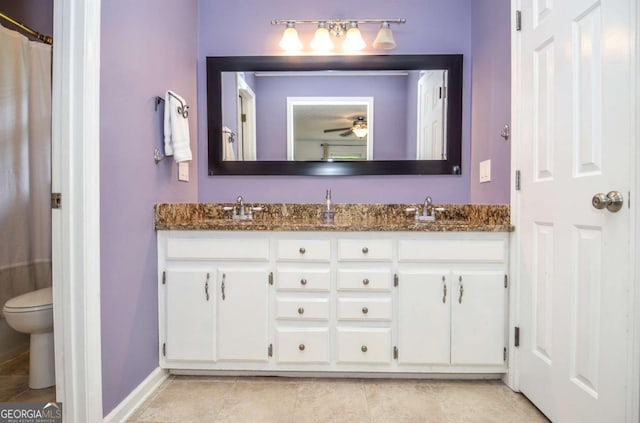 bathroom featuring double vanity, toilet, baseboards, and tile patterned flooring