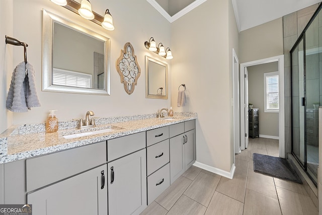 bathroom featuring a stall shower, double vanity, crown molding, and baseboards