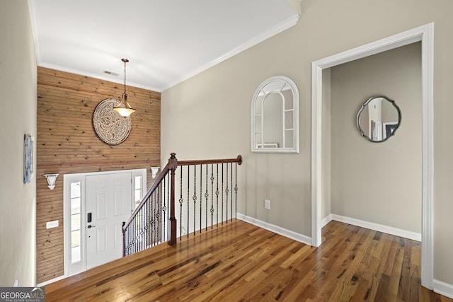 entrance foyer with baseboards, wood finished floors, crown molding, and wooden walls