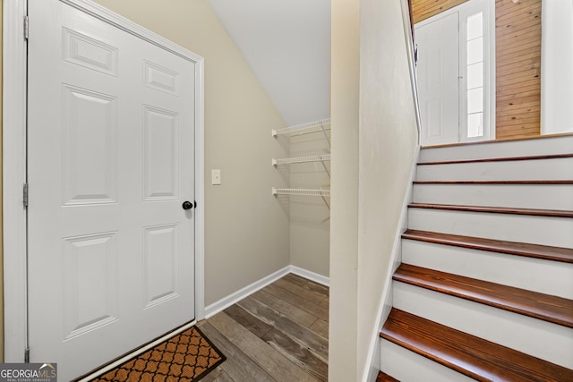 staircase featuring wood finished floors, vaulted ceiling, and baseboards