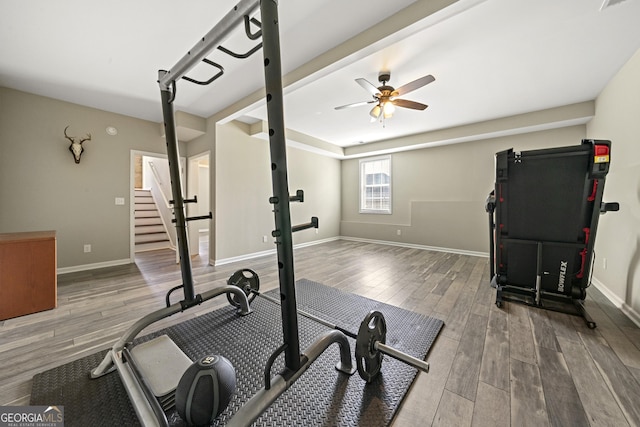 workout area featuring wood finished floors, a ceiling fan, and baseboards