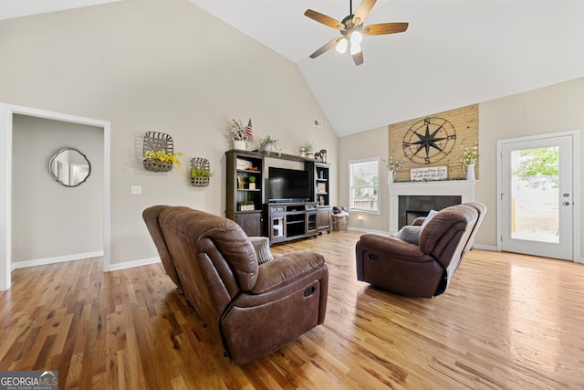 living room featuring high vaulted ceiling, wood finished floors, a ceiling fan, a fireplace, and baseboards