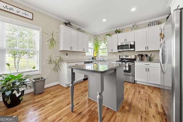 kitchen featuring appliances with stainless steel finishes, ornamental molding, white cabinets, a center island, and recessed lighting
