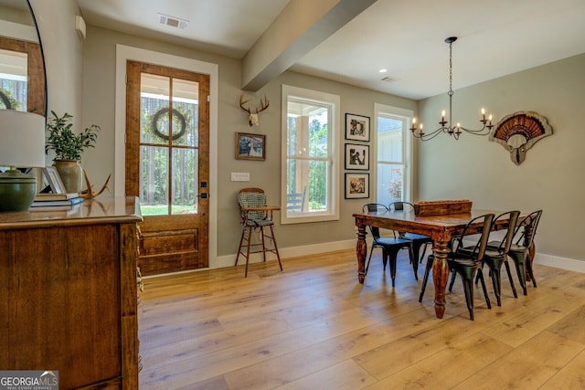 dining room featuring healthy amount of natural light, baseboards, a chandelier, and light wood-type flooring