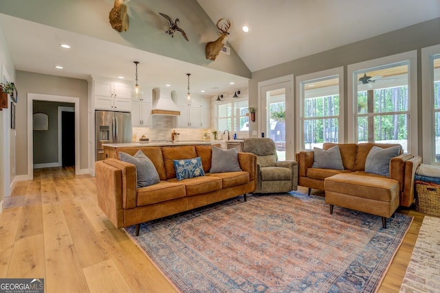 living room featuring light wood finished floors, recessed lighting, lofted ceiling, and baseboards
