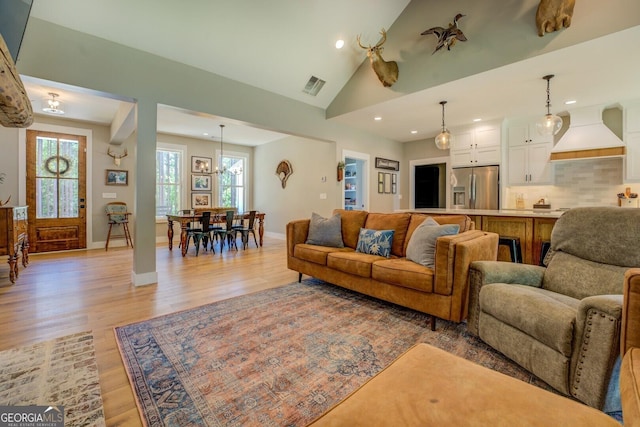 living room featuring recessed lighting, light wood-style flooring, baseboards, and vaulted ceiling