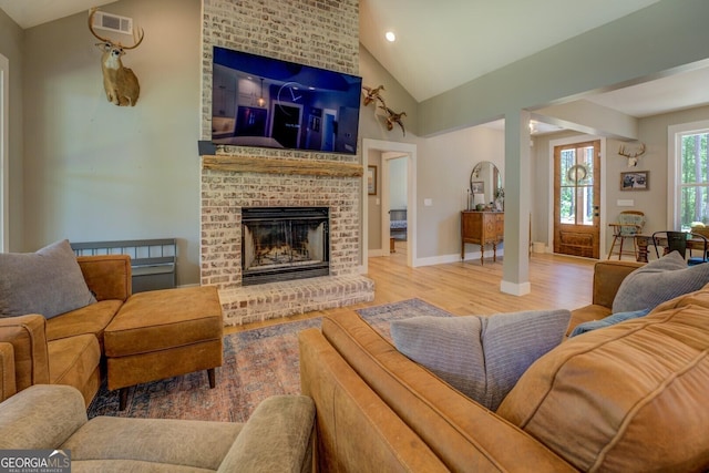 living room with lofted ceiling, wood finished floors, a brick fireplace, baseboards, and recessed lighting