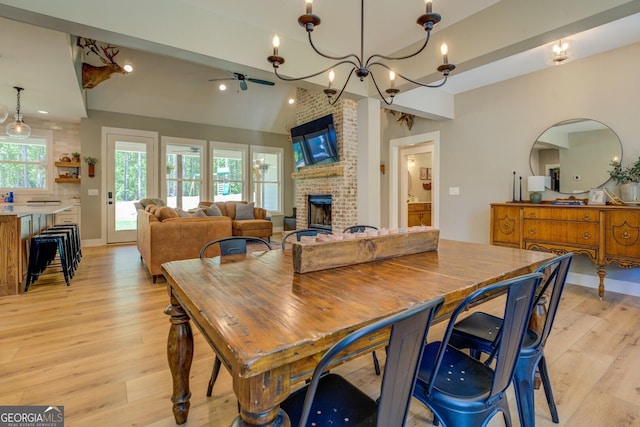 dining space with a brick fireplace, light wood-style floors, arched walkways, vaulted ceiling, and recessed lighting