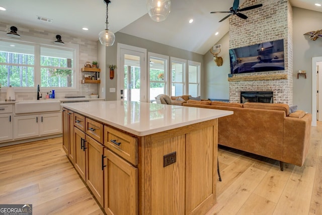 kitchen with a sink, a ceiling fan, open floor plan, a brick fireplace, and recessed lighting