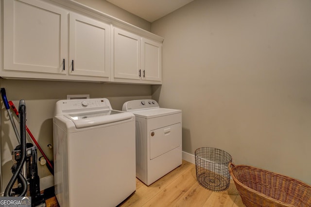 washroom featuring washer and dryer, cabinet space, light wood-style flooring, and baseboards