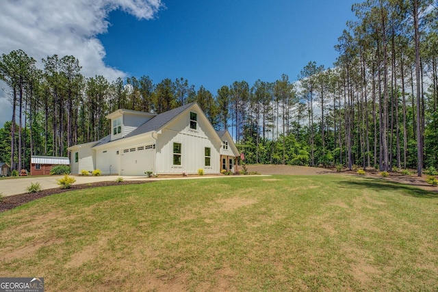 view of side of property featuring board and batten siding, a garage, a lawn, and driveway